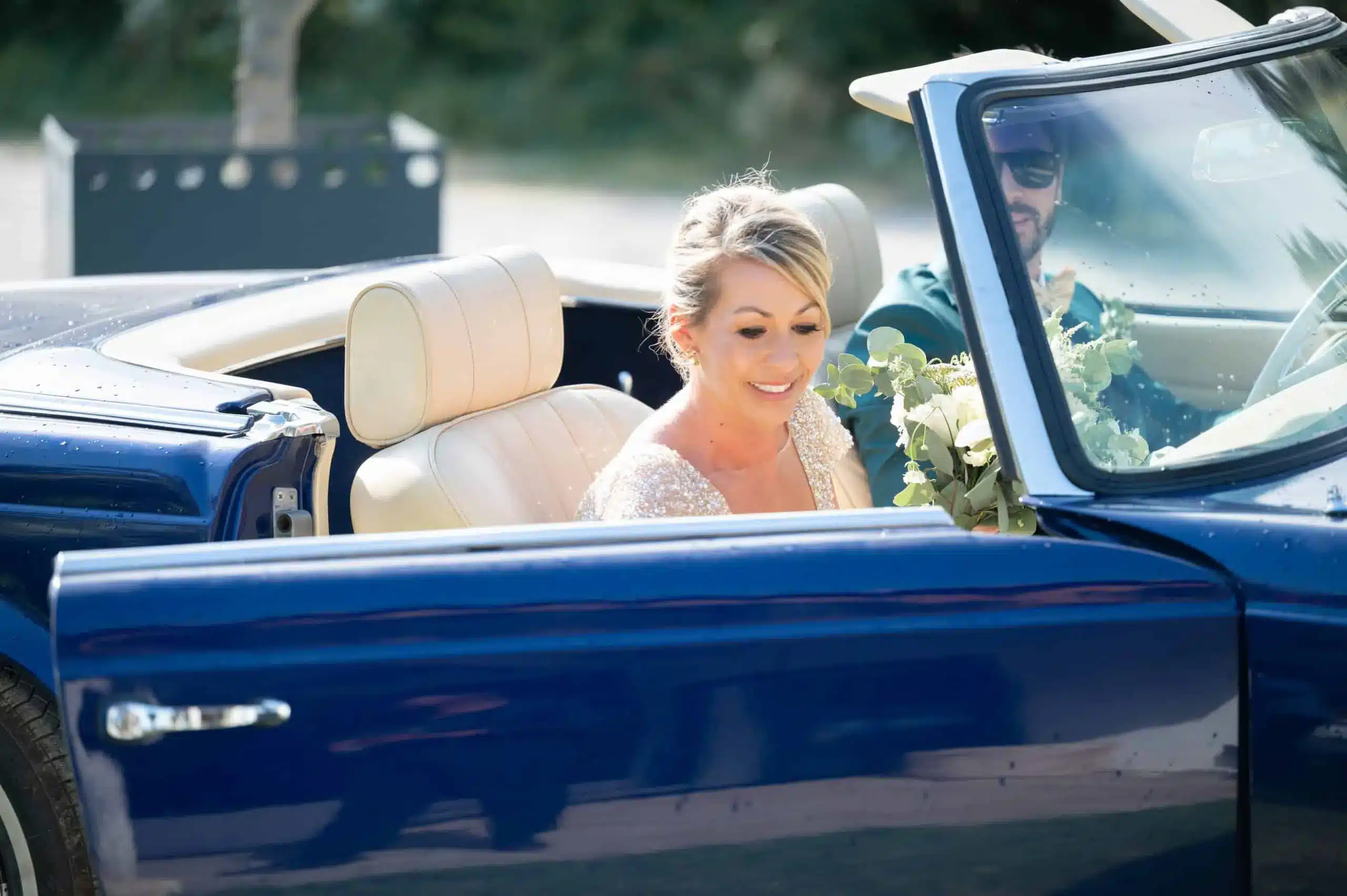 Organisateur de mariage en Camargue : les mariés rayonnent de bonheur dans une Mercedes vintage bleue, un choix parfait orchestré par leur wedding planner pour célébrer ce jour unique."