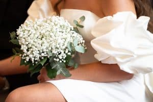 La mariée, assise à la mairie d’Uzès dans le Gard , tient son bouquet de gypsophile lors de son mariage civil, organisé par Version Luxe Evenements , wedding planner